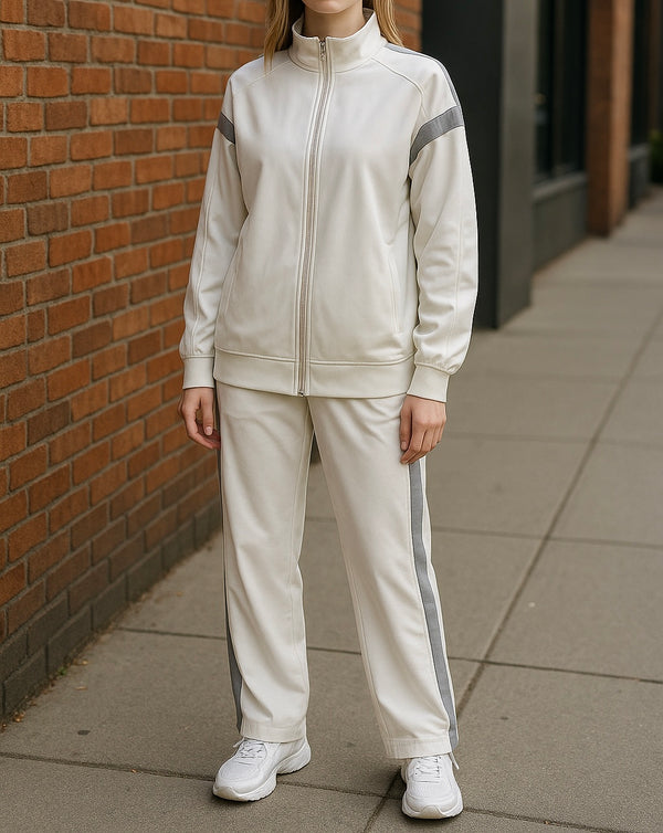 Modest two-piece pajama set in cream with grey side stripes, featuring a zip-up high-collar top and relaxed-fit pants, styled with white sneakers