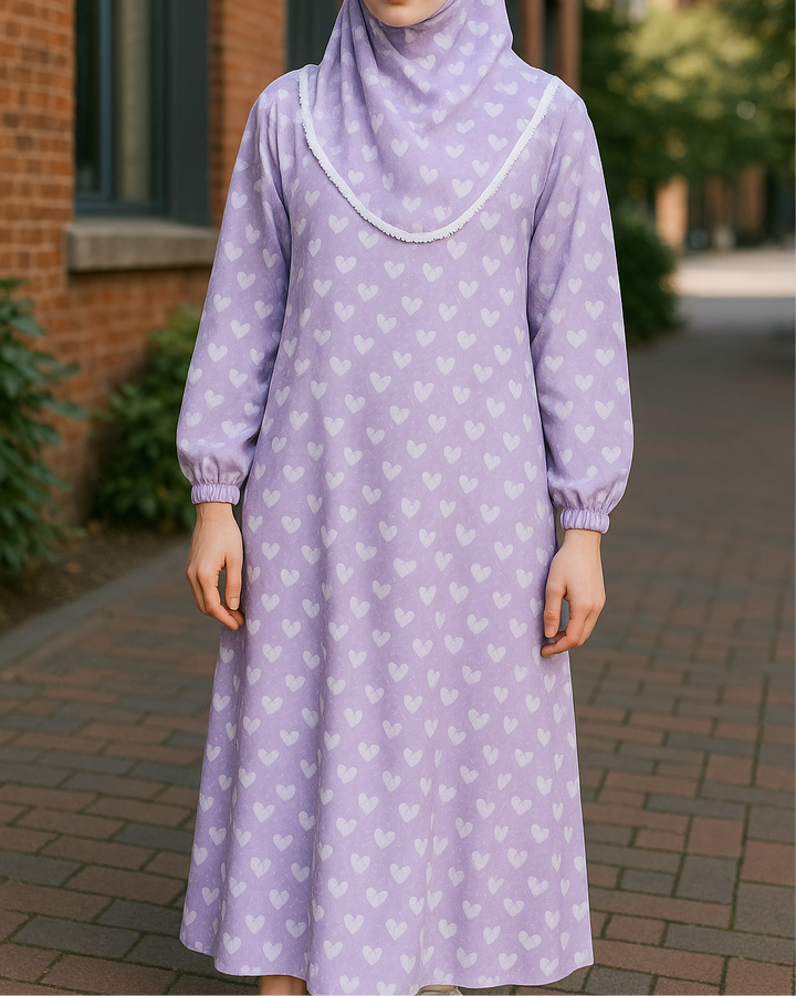 Jeune fille portant une robe de prière lilas avec motifs cœurs blancs et khimar assorti – tenue modeste disponible de 8 à 15 ans.