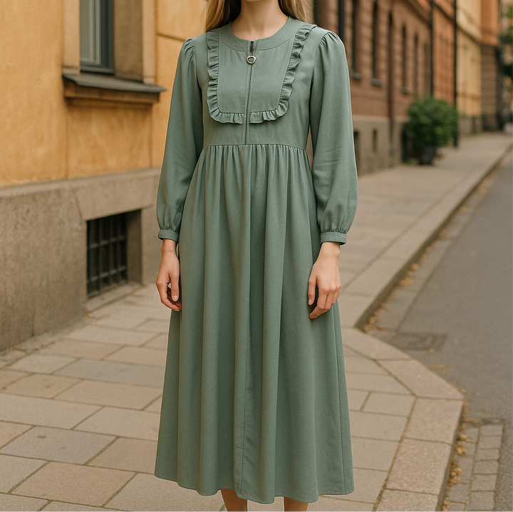 Jeune fille portant une robe vert sauge longue à manches longues, avec plastron à volants et bouton décoratif – tenue disponible de 8 à 15 ans