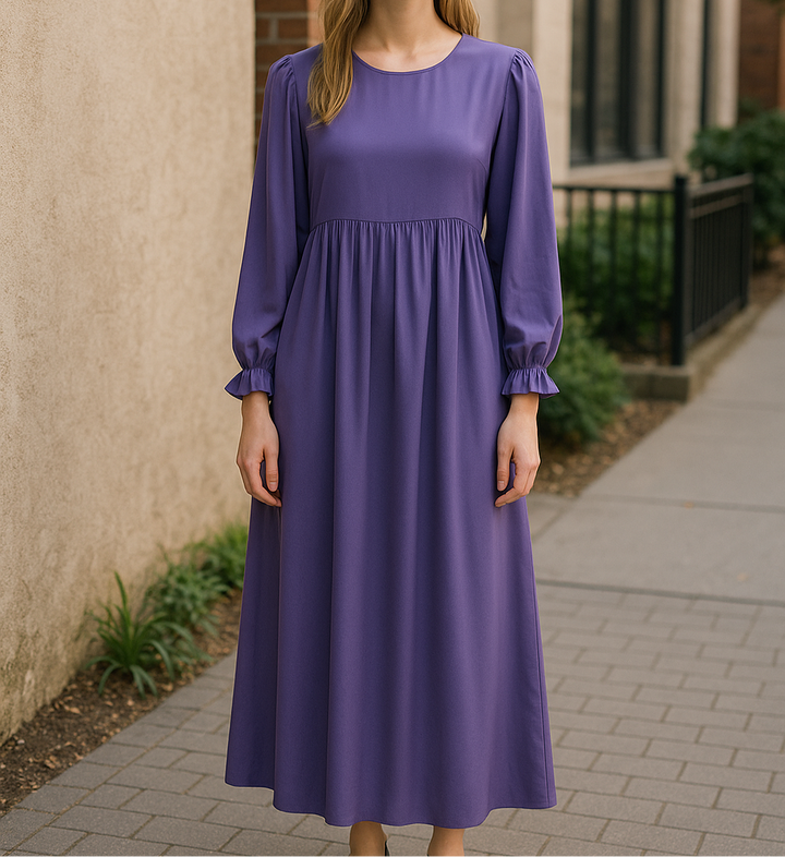 Fille portant une abaya violette longue à manches bouffantes, posant dehors devant un mur en brique