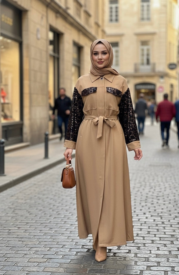 Femme portant une élégante robe-manteau longue de couleur camel avec des manches noires à motifs et une ceinture assortie.
