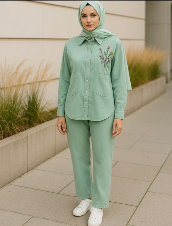 A hijabi girl wears a Two-piece modest outfit in mint green with button-down top, floral embroidery on the chest, and straight-leg pants, styled with white sneakers