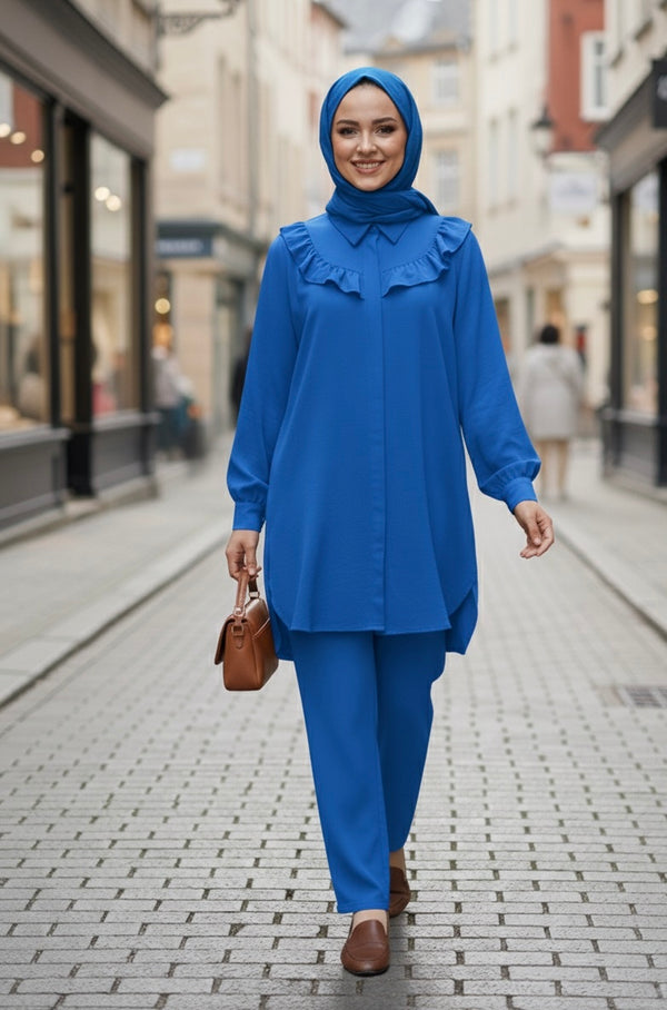 Femme souriante portant un ensemble deux-pièces bleu roi composé d'une tunique à volants et d'un pantalon assorti.