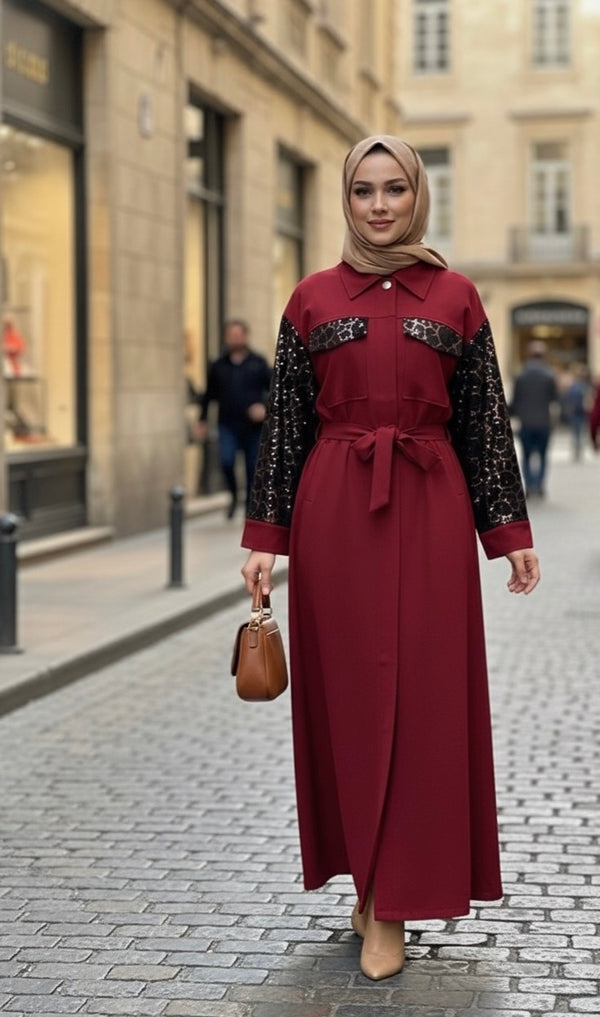 Femme portant une longue robe-manteau de couleur bordeaux avec des manches noires à motifs et une ceinture assortie.
