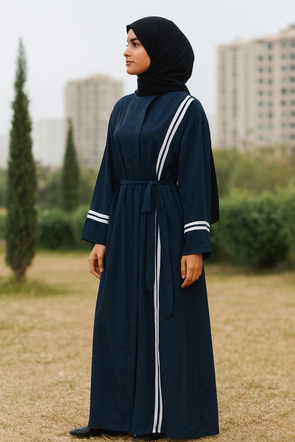 Femme hijabi portant une abaya bleu marine à rayures blanches avec ceinture ajustable, style sport chic.